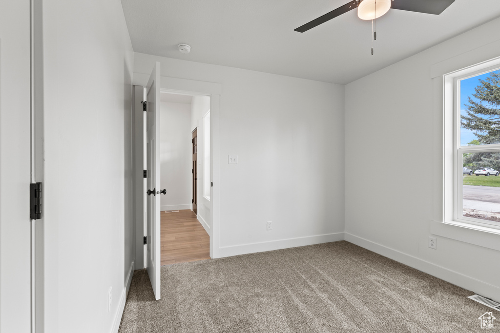 Carpeted empty room with a ceiling fan and baseboards