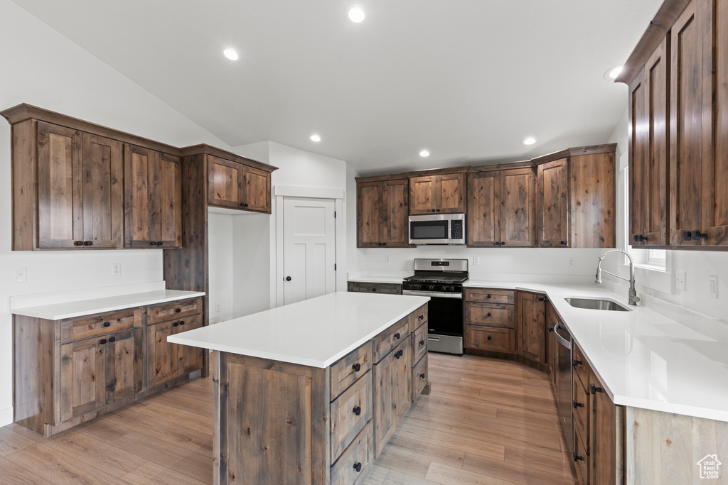 Kitchen featuring appliances with stainless steel finishes, a sink, light wood-style floors, a center island, and recessed lighting