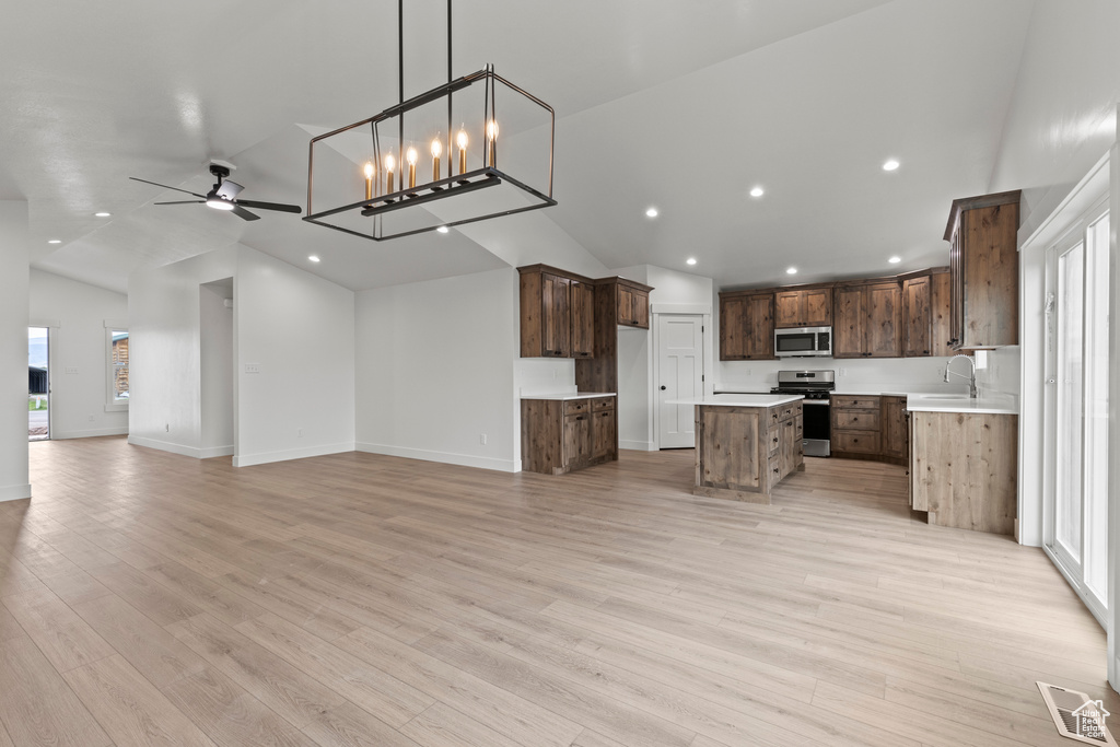 Kitchen featuring stainless steel appliances, open floor plan, a center island, a sink, and light wood-type flooring