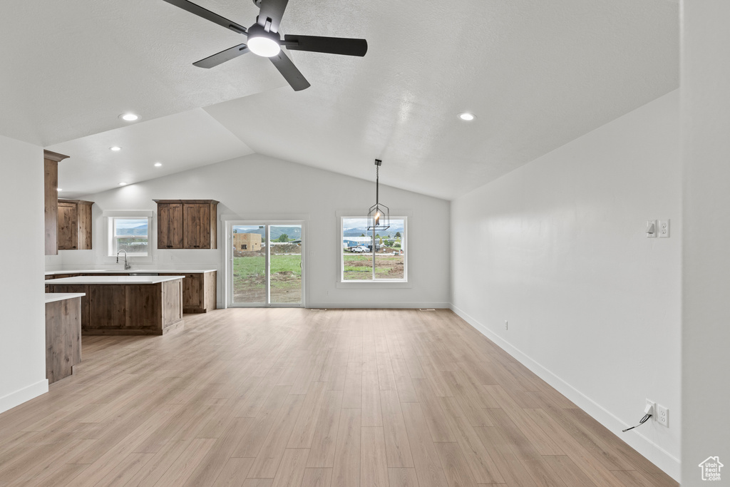 Unfurnished living room with a sink, lofted ceiling, recessed lighting, light wood-type flooring, and a ceiling fan