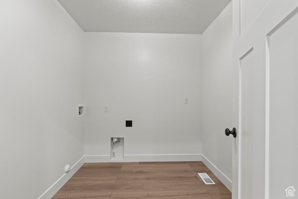 Laundry room featuring hookup for a washing machine, light wood finished floors, baseboards, and a textured ceiling