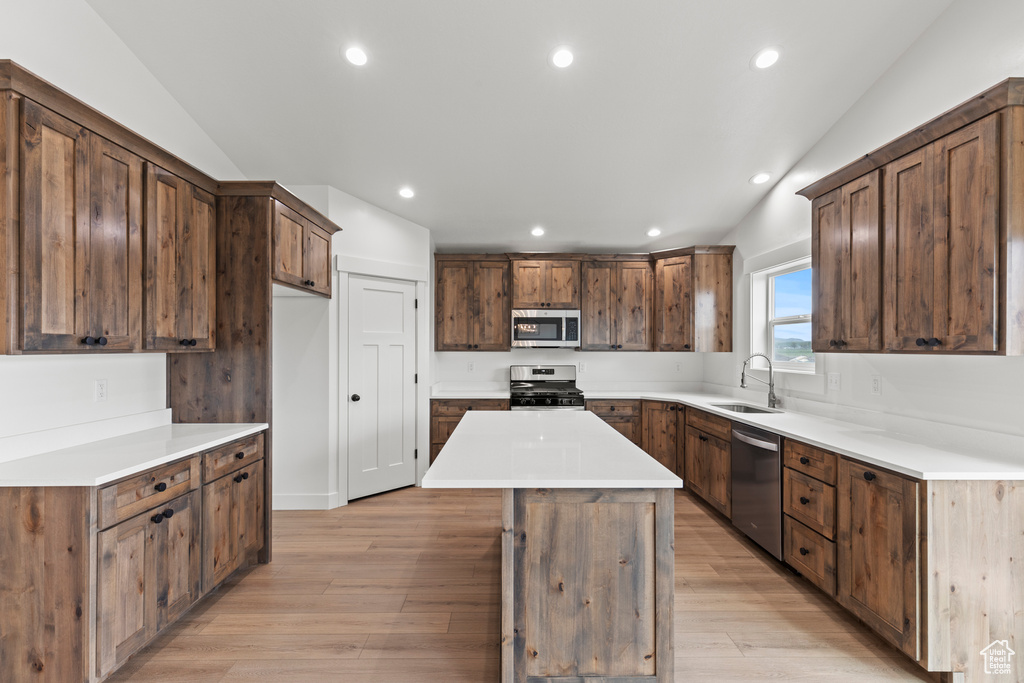 Kitchen with stainless steel appliances, a sink, a kitchen island, light wood-type flooring, and recessed lighting