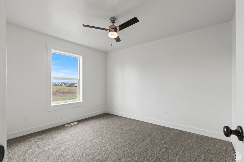 Empty room featuring carpet, baseboards, and a ceiling fan