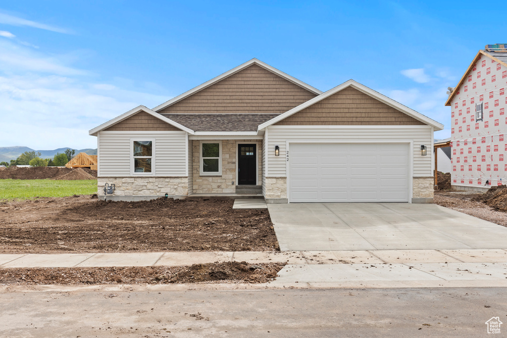 Craftsman-style home featuring an attached garage, concrete driveway, and stone siding