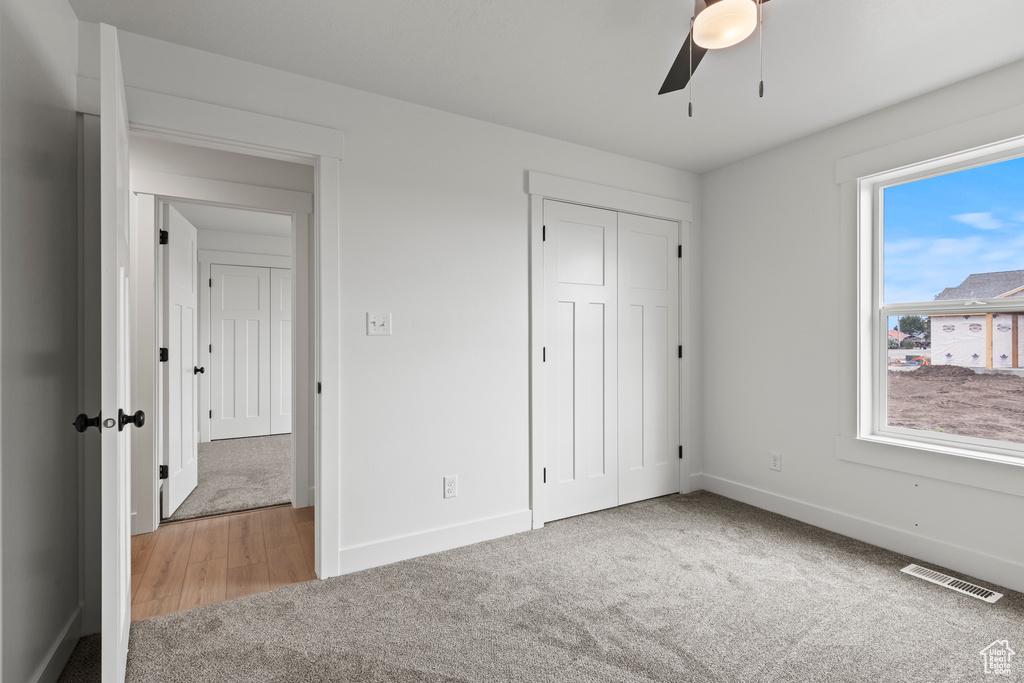 Unfurnished bedroom with carpet flooring, baseboards, a closet, and a ceiling fan