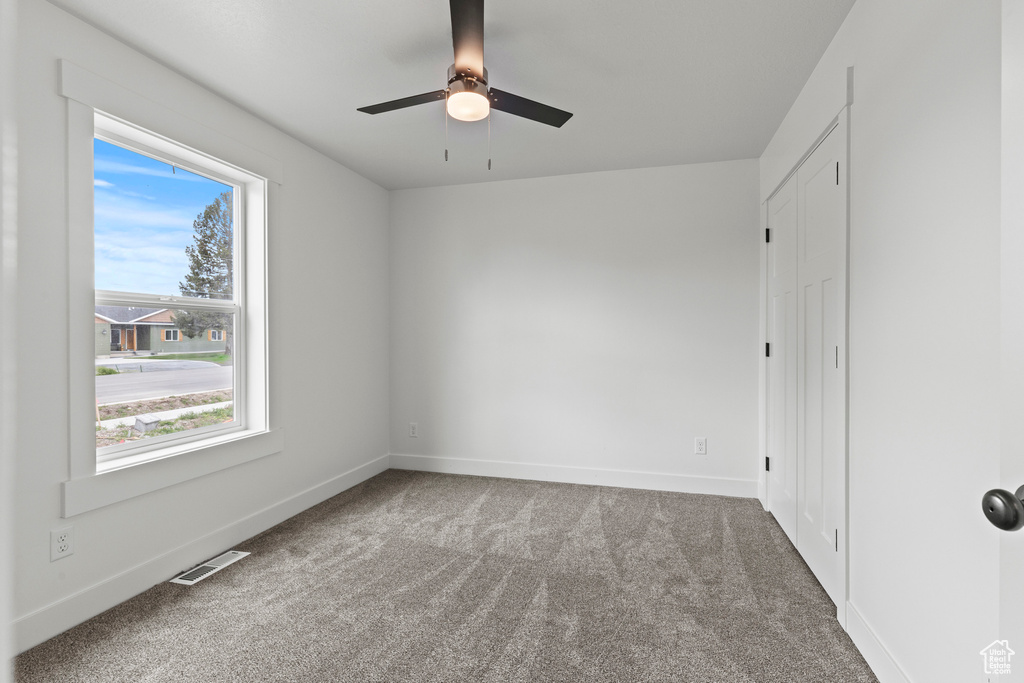 Carpeted spare room with ceiling fan and baseboards
