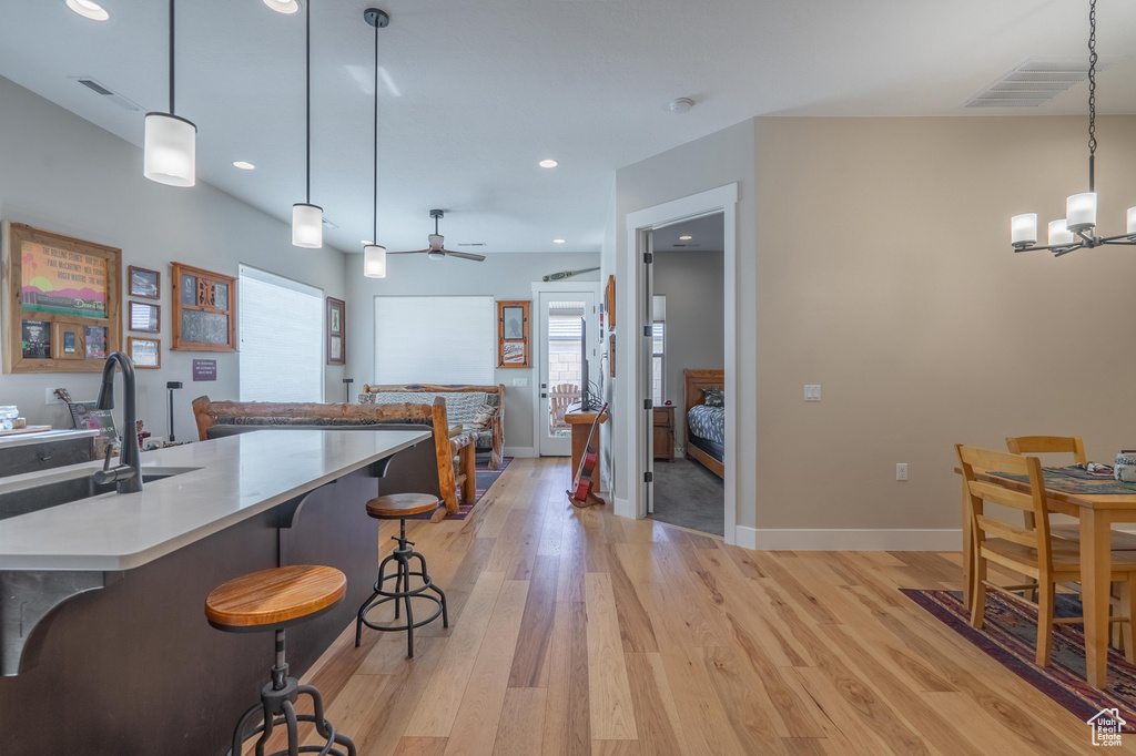 Kitchen featuring light wood-type flooring, a chandelier, a breakfast bar, recessed lighting, and light countertops