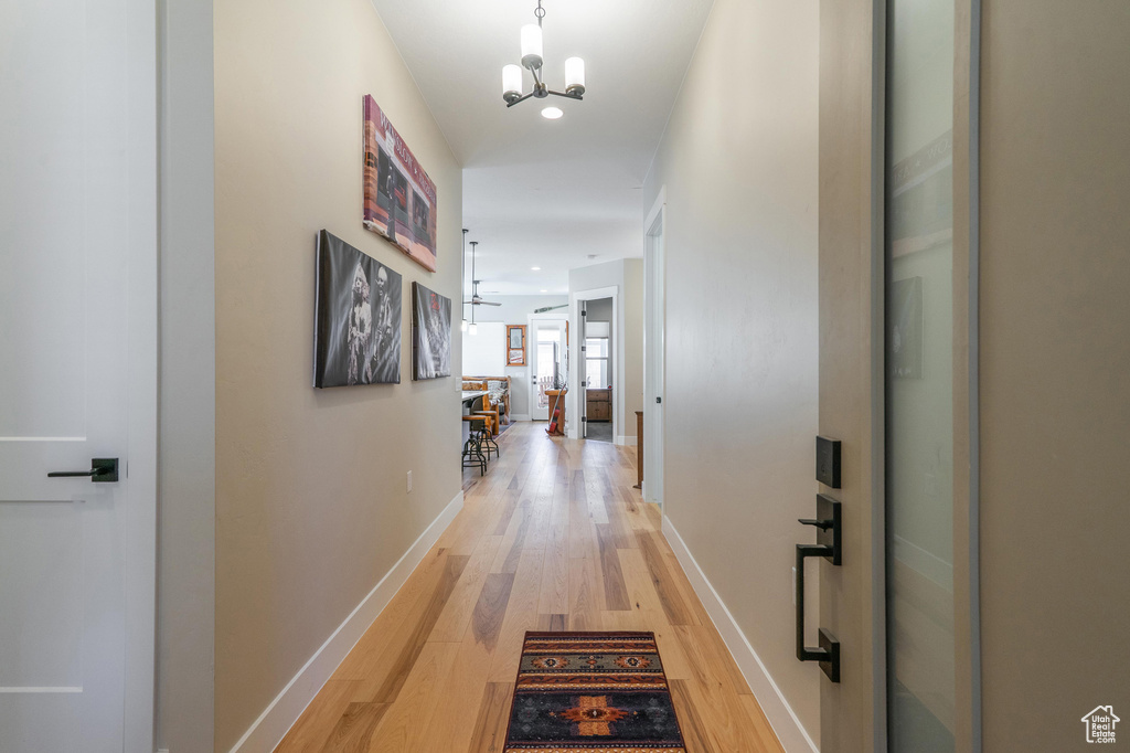 Hall with light wood-style floors, a chandelier, baseboards, and recessed lighting
