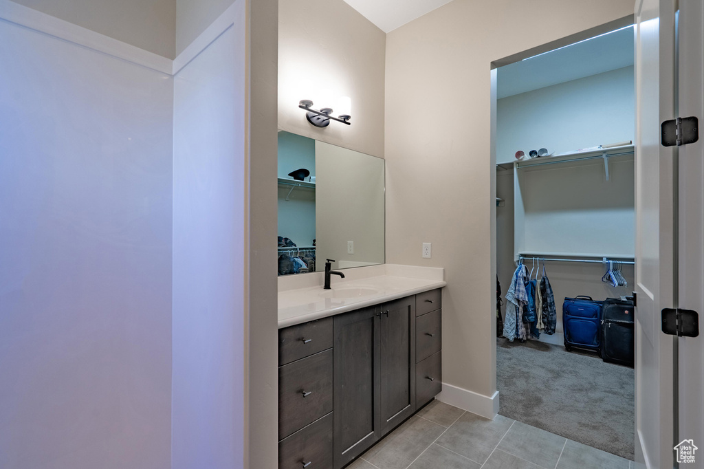 Bathroom featuring vanity, tile patterned floors, a spacious closet, and baseboards