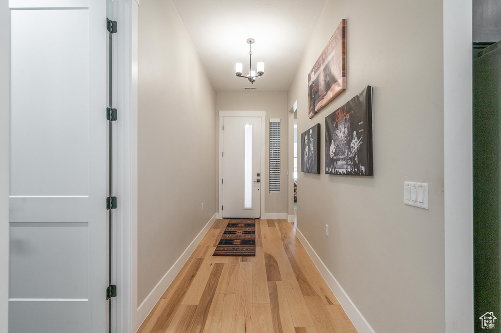 Entryway with light wood-style flooring, a chandelier, and baseboards