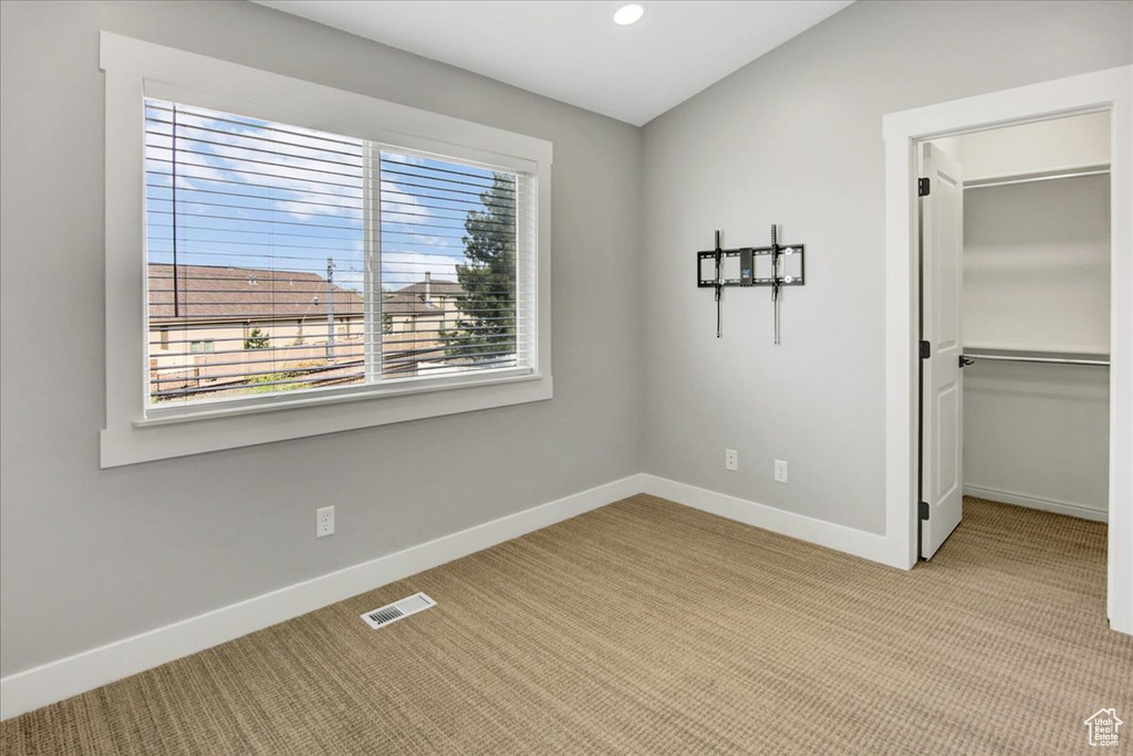 Unfurnished bedroom with light colored carpet, baseboards, a walk in closet, recessed lighting, and a closet