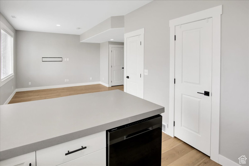 Kitchen featuring black dishwasher, light wood-style flooring, baseboards, white cabinets, and recessed lighting