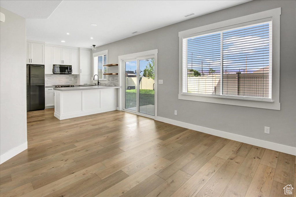 Kitchen featuring refrigerator, stainless steel microwave, recessed lighting, baseboards, and backsplash