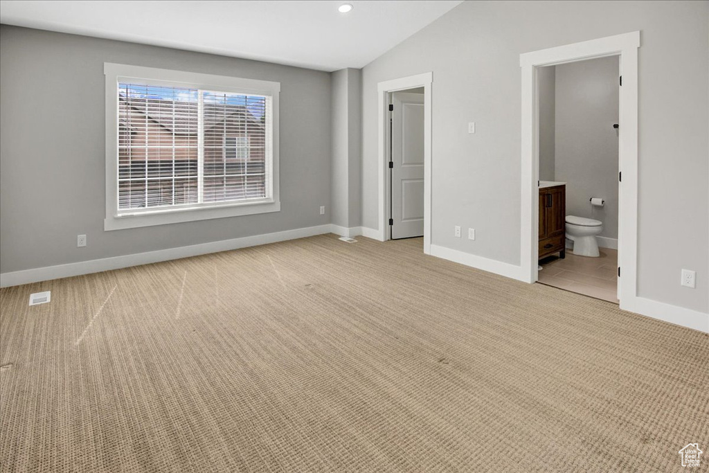 Unfurnished bedroom featuring light colored carpet, vaulted ceiling, baseboards, ensuite bathroom, and recessed lighting