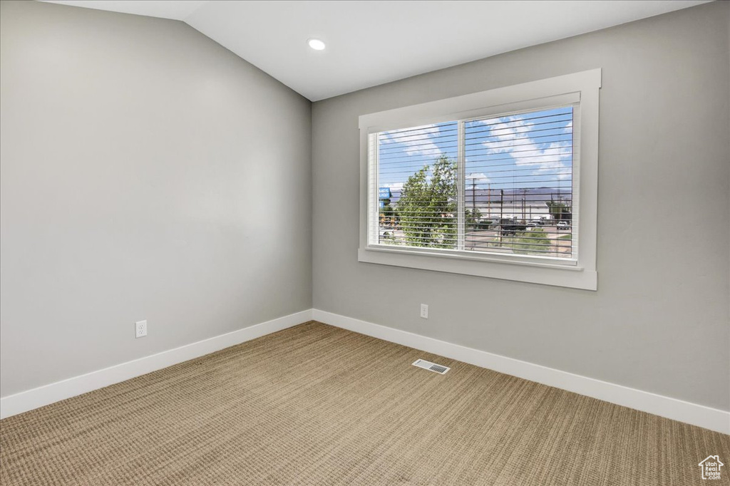 Carpeted empty room featuring baseboards, recessed lighting, and vaulted ceiling