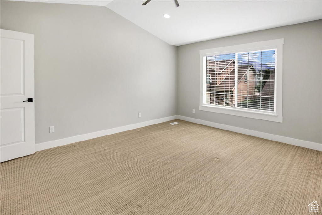 Empty room featuring light colored carpet, vaulted ceiling, baseboards, and recessed lighting