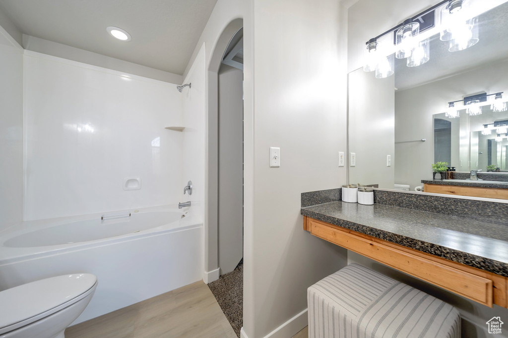 Bathroom featuring wood finished floors, shower / bathtub combination, toilet, baseboards, and vanity