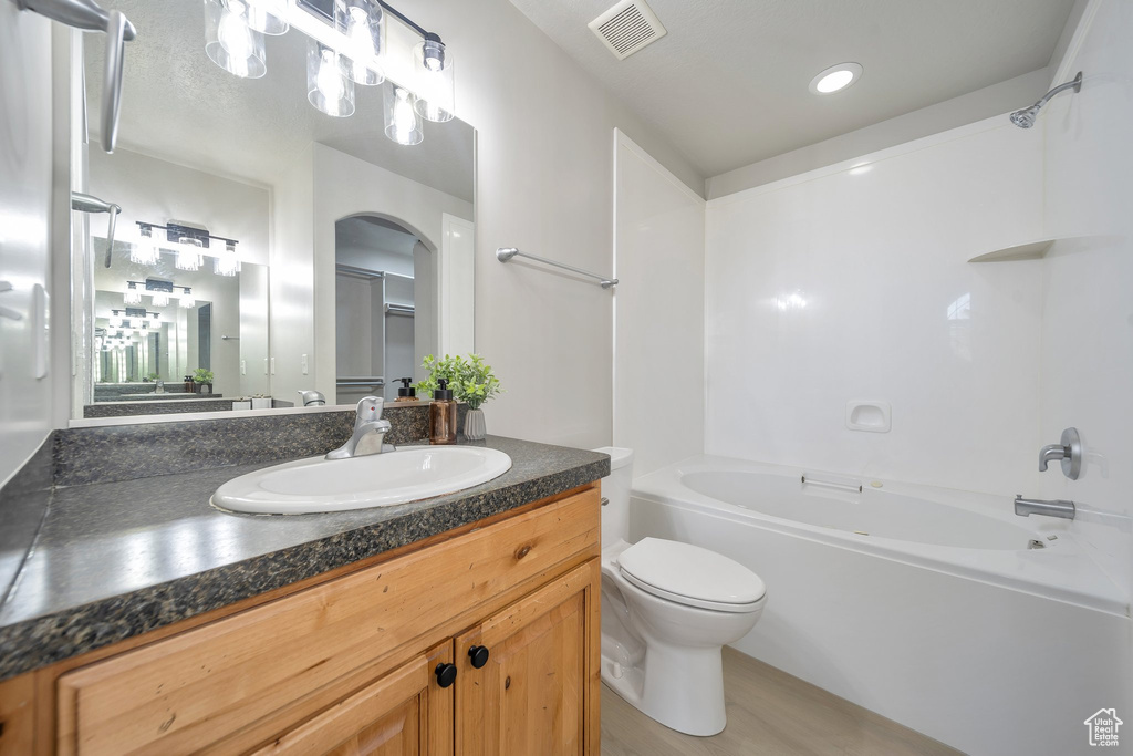 Bathroom featuring bathtub / shower combination, toilet, vanity, and wood finished floors