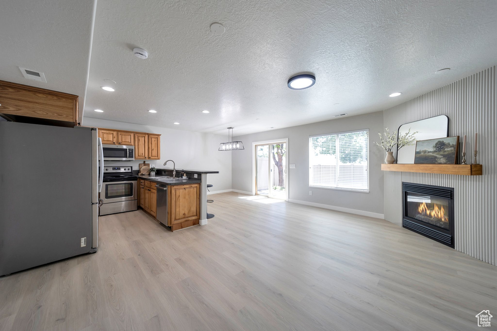 Kitchen featuring stainless steel appliances, a sink, dark countertops, open floor plan, and recessed lighting