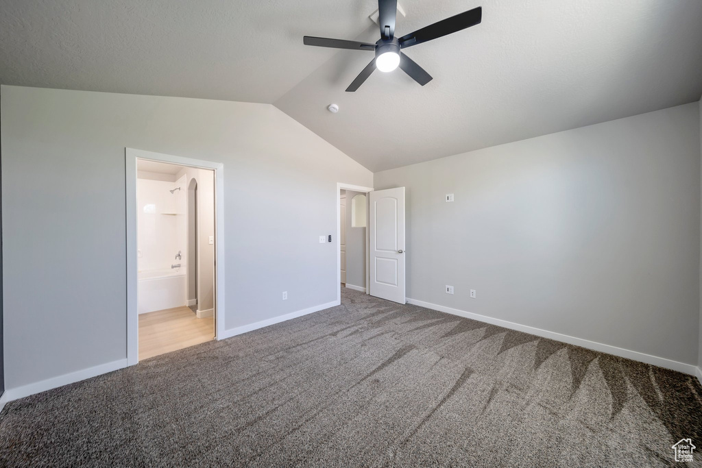 Unfurnished bedroom with carpet floors, vaulted ceiling, baseboards, ensuite bath, and a ceiling fan