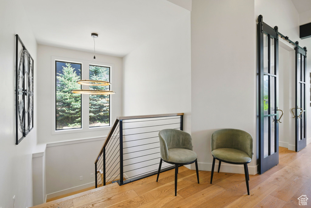 Living area featuring wood finished floors, baseboards, a barn door, and an upstairs landing