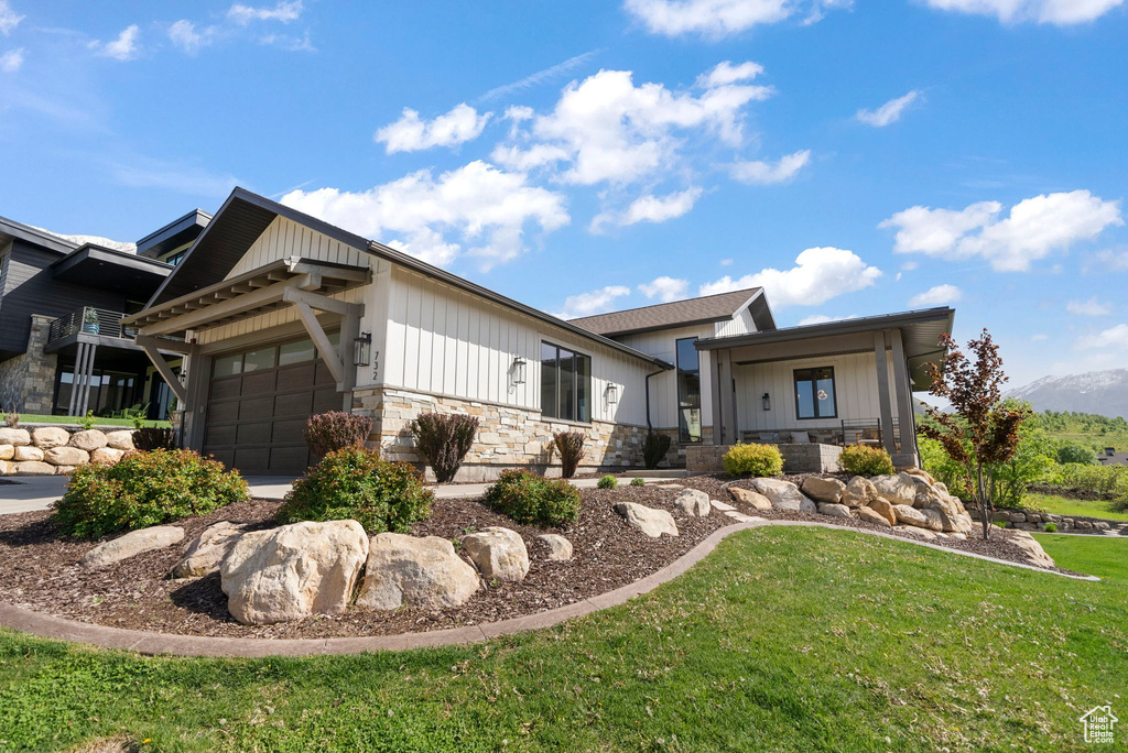 View of front of house featuring stone siding, a garage, and a front lawn