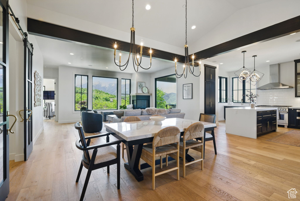 Dining space featuring light wood-style flooring, a chandelier, recessed lighting, a barn door, and lofted ceiling