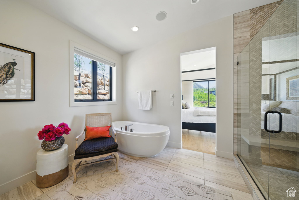 Ensuite bathroom with baseboards, a shower stall, a soaking tub, recessed lighting, and tile patterned floors