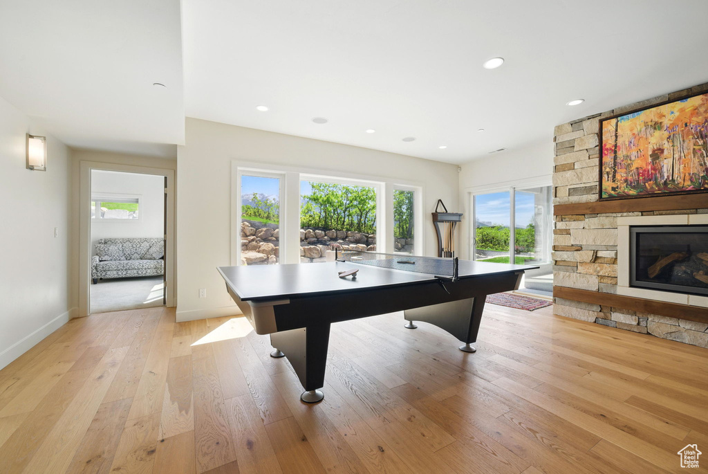 Game room with light wood-type flooring, a stone fireplace, baseboards, and recessed lighting