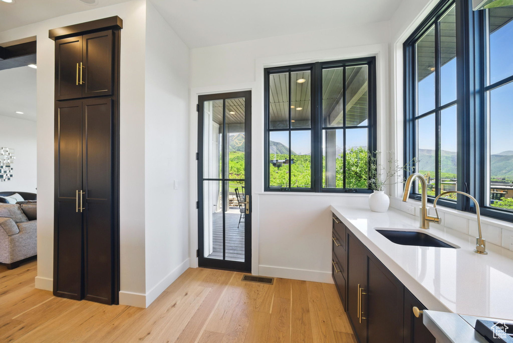 Doorway to outside with a sink, baseboards, and light wood-type flooring