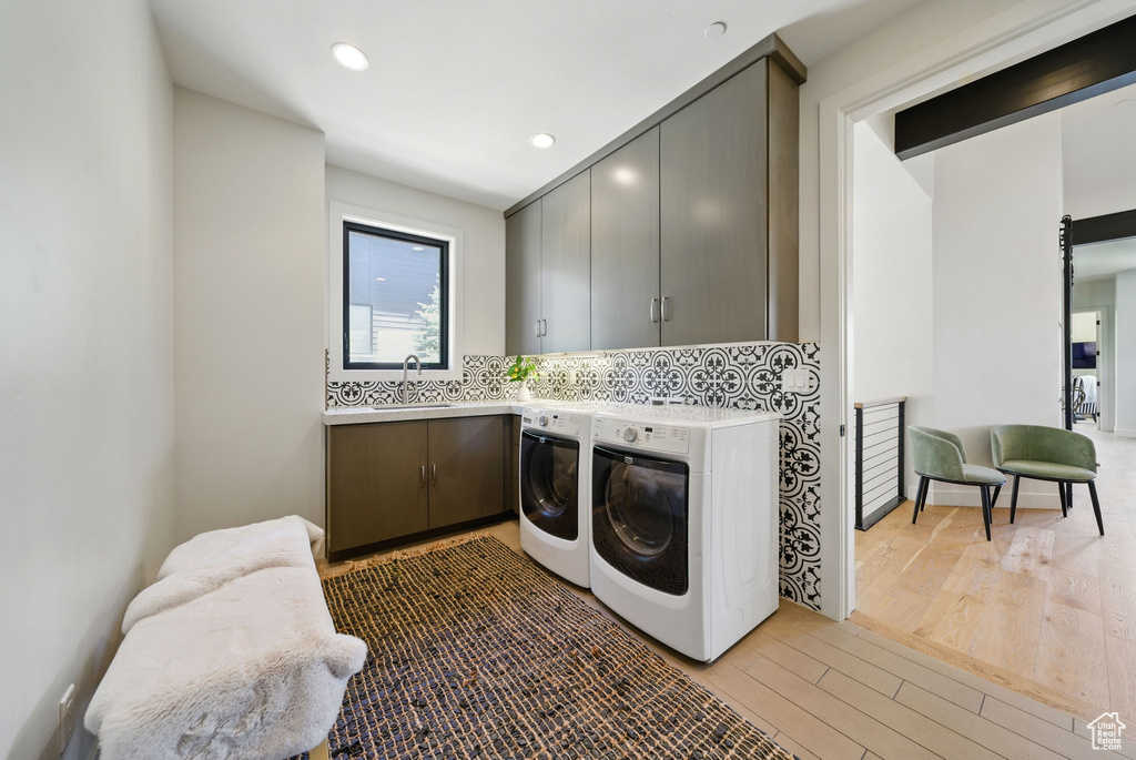 Clothes washing area with cabinet space, washer and dryer, wood finished floors, and recessed lighting