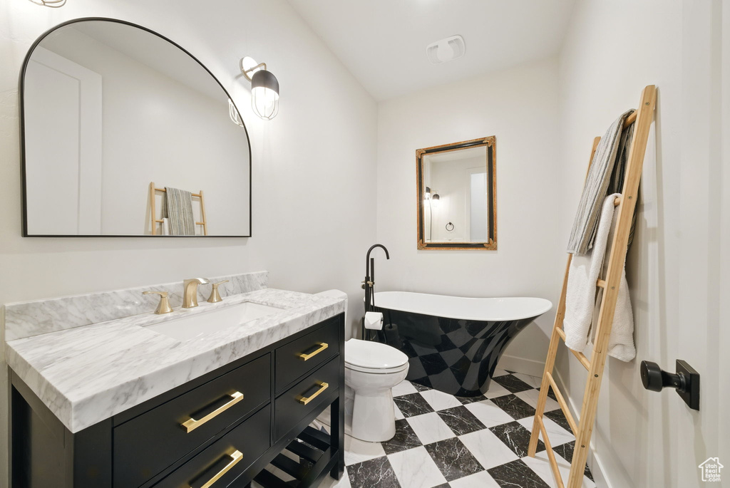 Bathroom with a soaking tub, vanity, baseboards, toilet, and tile patterned floors