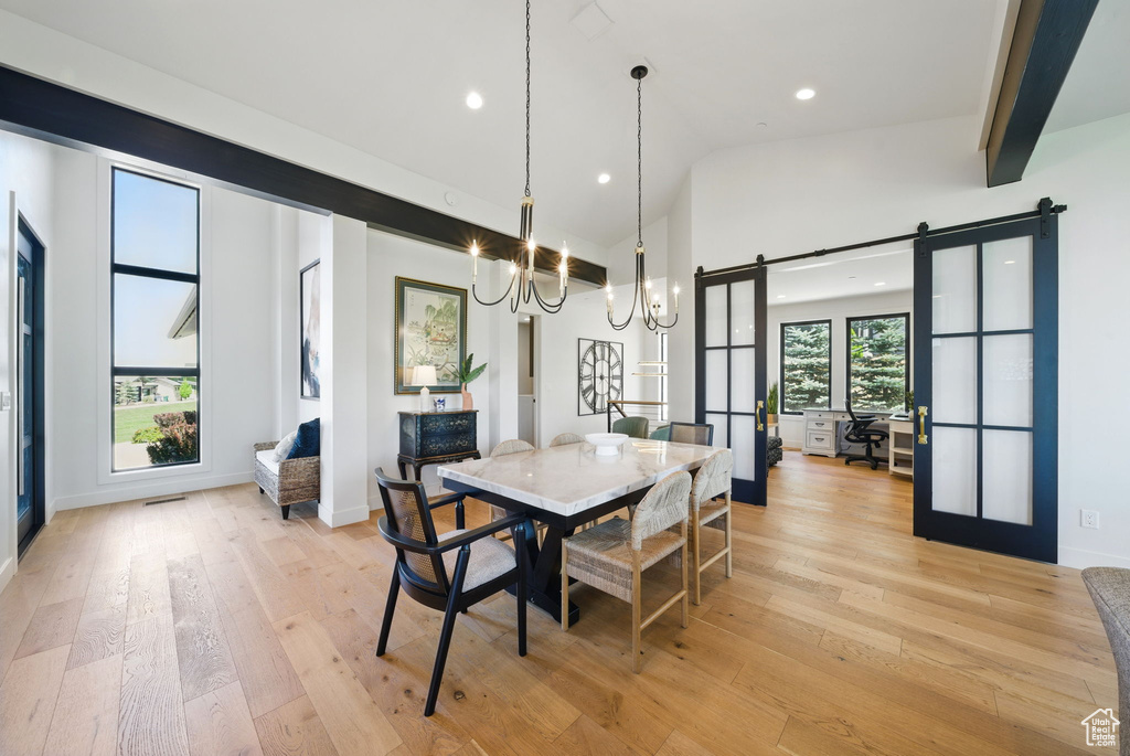 Dining space featuring a barn door, a chandelier, recessed lighting, light wood finished floors, and high vaulted ceiling