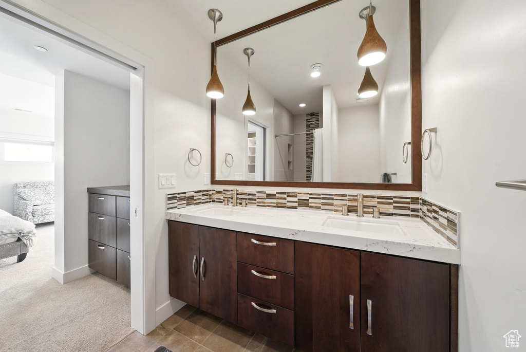 Full bath with tasteful backsplash, double vanity, and connected bathroom