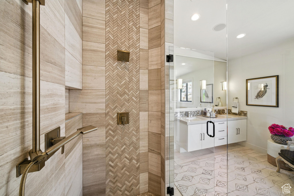 Full bathroom featuring a tile shower, vanity, recessed lighting, and baseboards