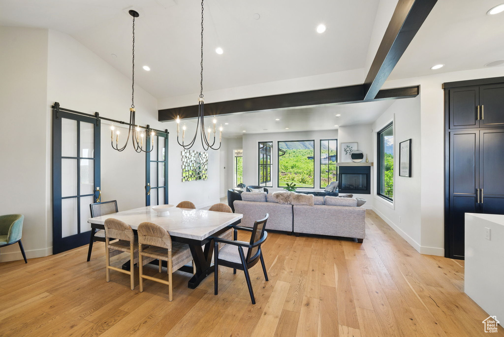 Dining area featuring a chandelier, light wood finished floors, recessed lighting, baseboards, and high vaulted ceiling