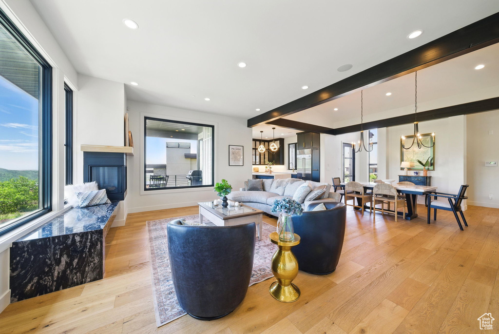 Living area featuring a chandelier, light wood-style flooring, recessed lighting, baseboards, and a glass covered fireplace