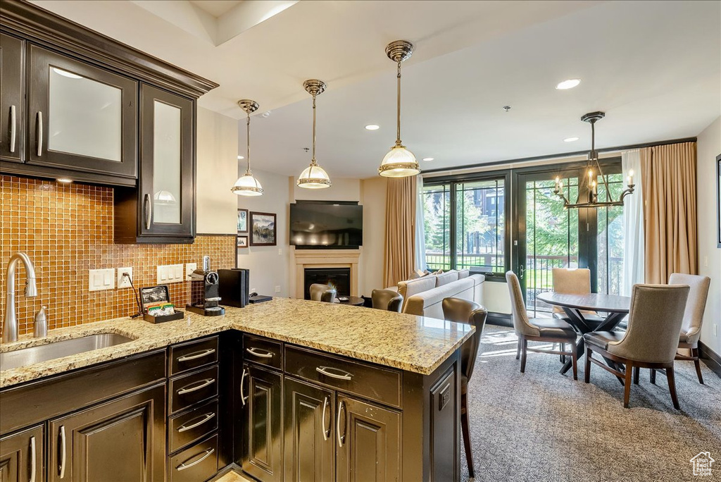 Kitchen with a sink, dark brown cabinets, glass insert cabinets, and tasteful backsplash