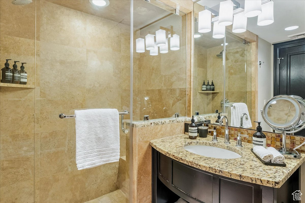 Bathroom featuring a stall shower, vanity, and tile walls