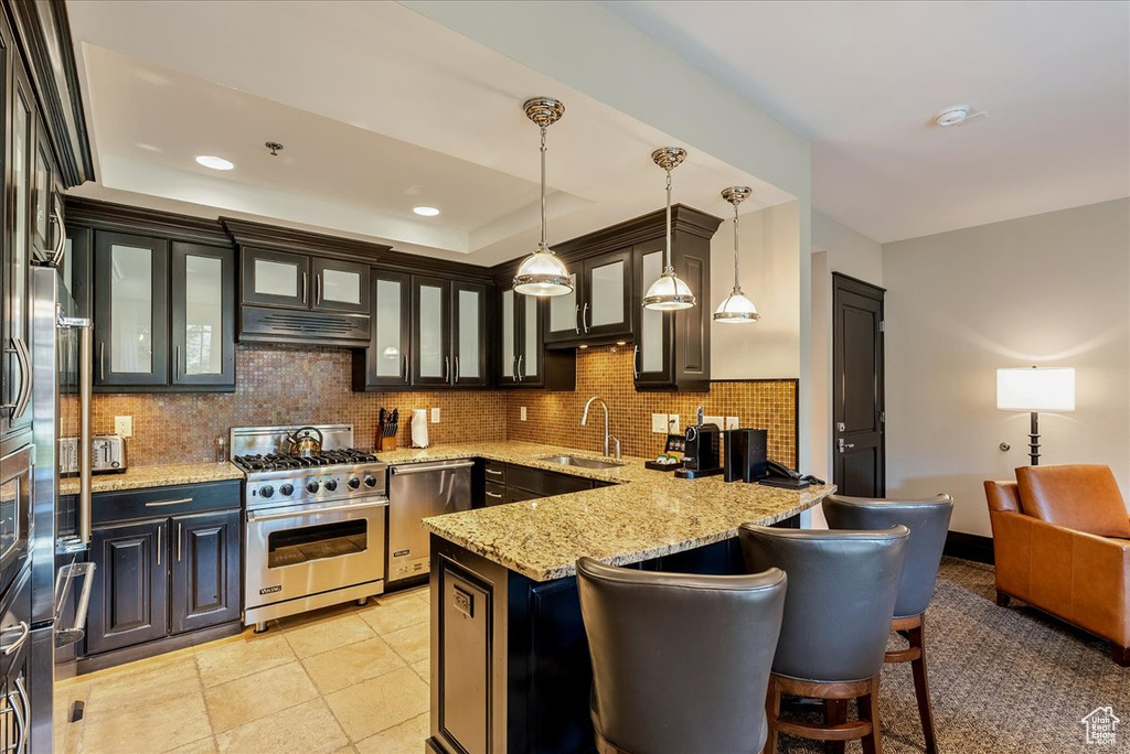 Kitchen with stainless steel appliances, a sink, tasteful backsplash, a peninsula, and decorative light fixtures