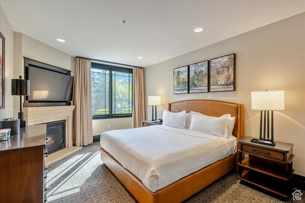 Bedroom with carpet floors, recessed lighting, a glass covered fireplace, and baseboards