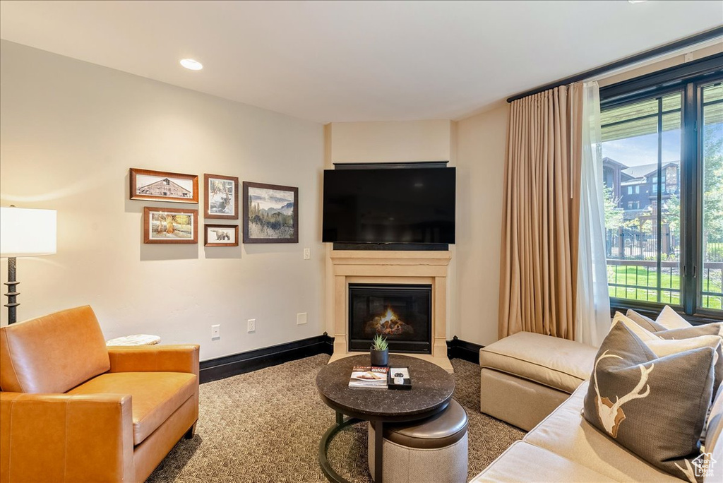 Living area featuring a fireplace with flush hearth, recessed lighting, baseboards, and carpet floors