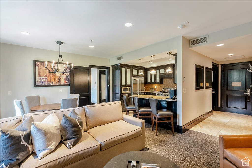 Living area with a chandelier, recessed lighting, baseboards, and light tile patterned flooring