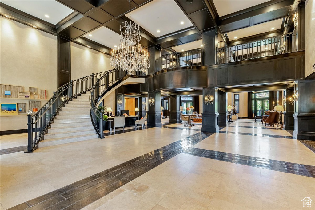 Common area featuring a high ceiling, stairs, coffered ceiling, and beamed ceiling