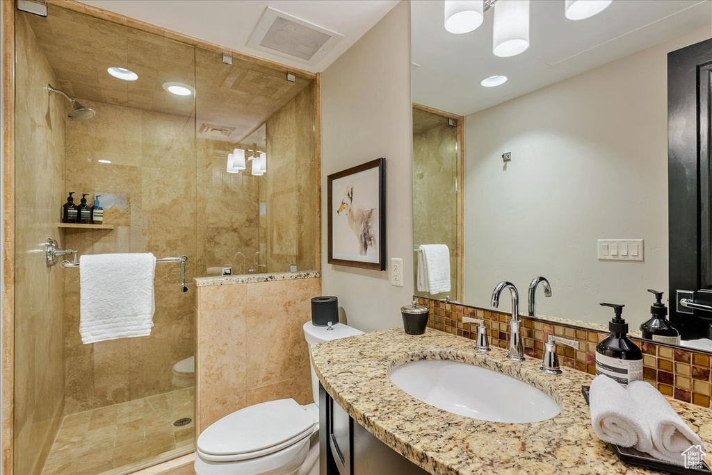 Bathroom featuring toilet, a stall shower, and vanity
