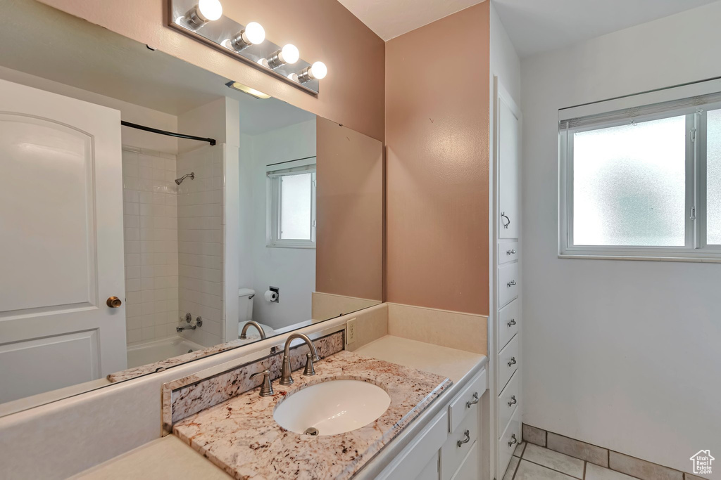 Full bath with healthy amount of natural light, tile patterned floors, vanity, and tub / shower combination