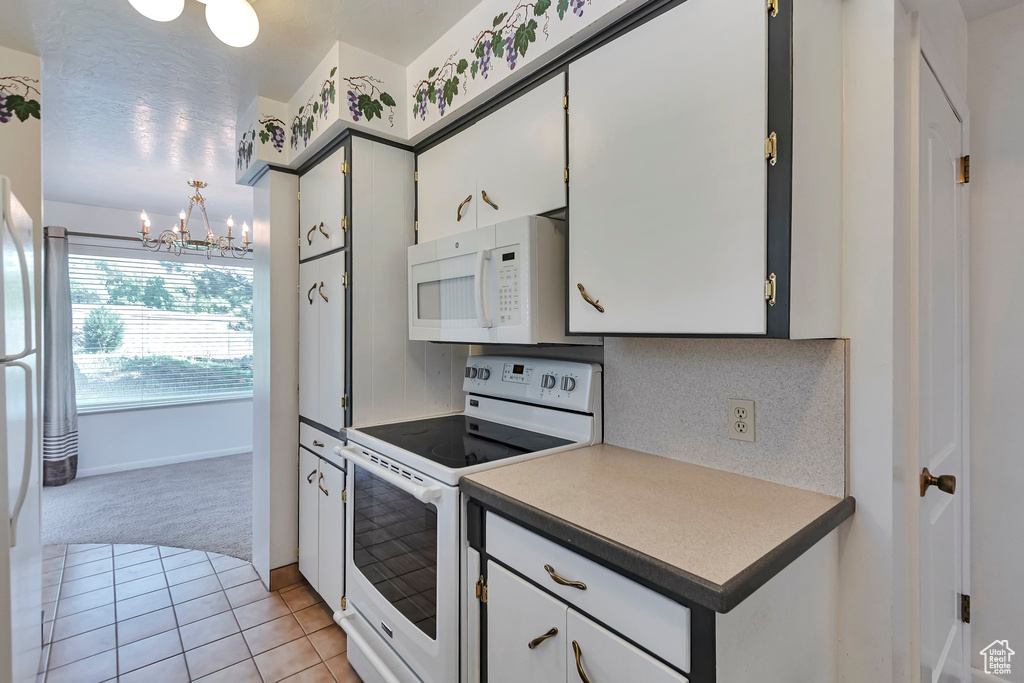 Kitchen featuring white appliances, light colored carpet, a chandelier, backsplash, and light tile patterned flooring