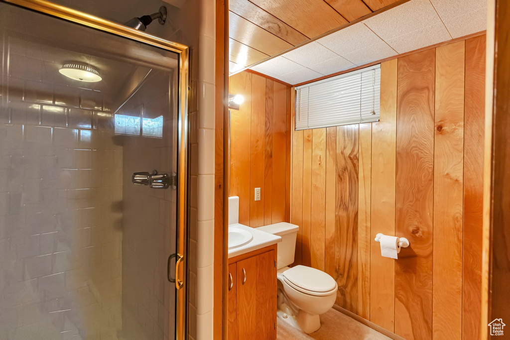 Full bath featuring toilet, a shower stall, wooden walls, and vanity