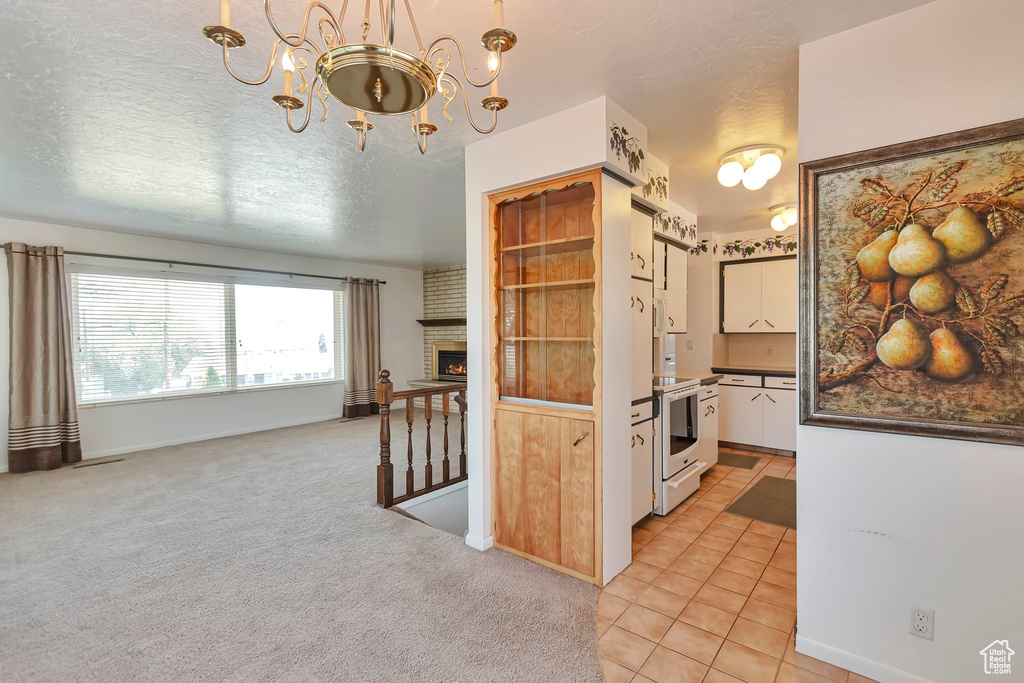 Kitchen with a chandelier, electric range, dark countertops, white cabinets, and open floor plan