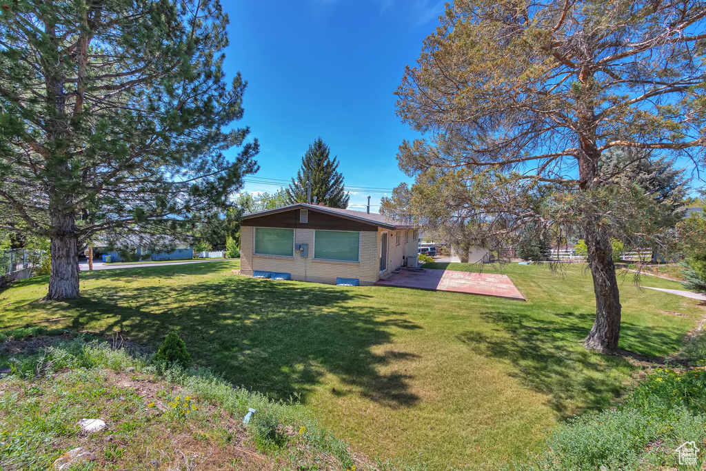 View of home\'s exterior with brick siding, a lawn, and a patio
